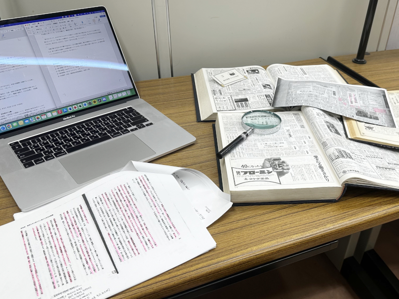 資料や新聞の縮刷版を広げている様子